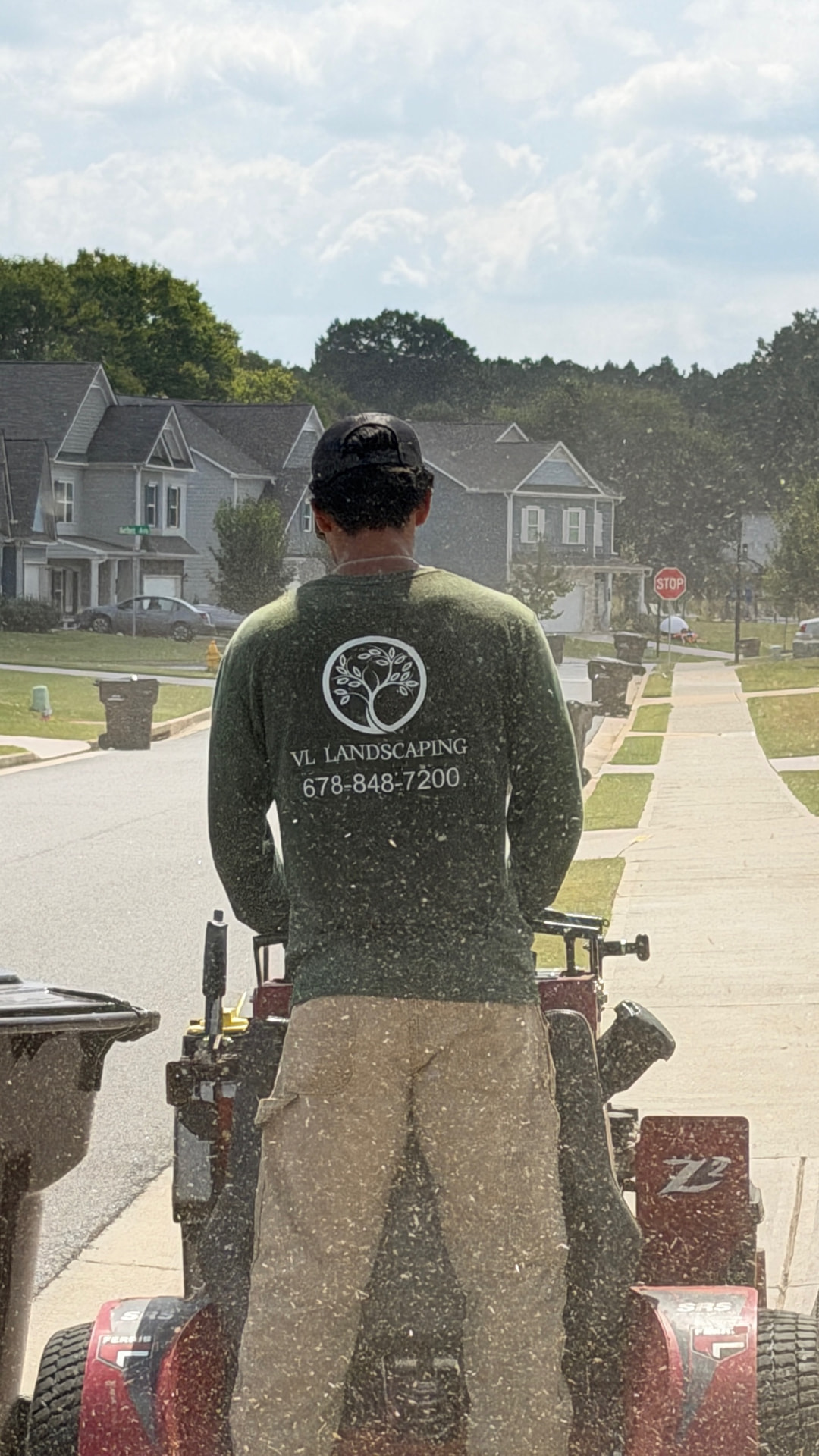 Crew member on a stand-on mower edging along a neighborhood sidewalk