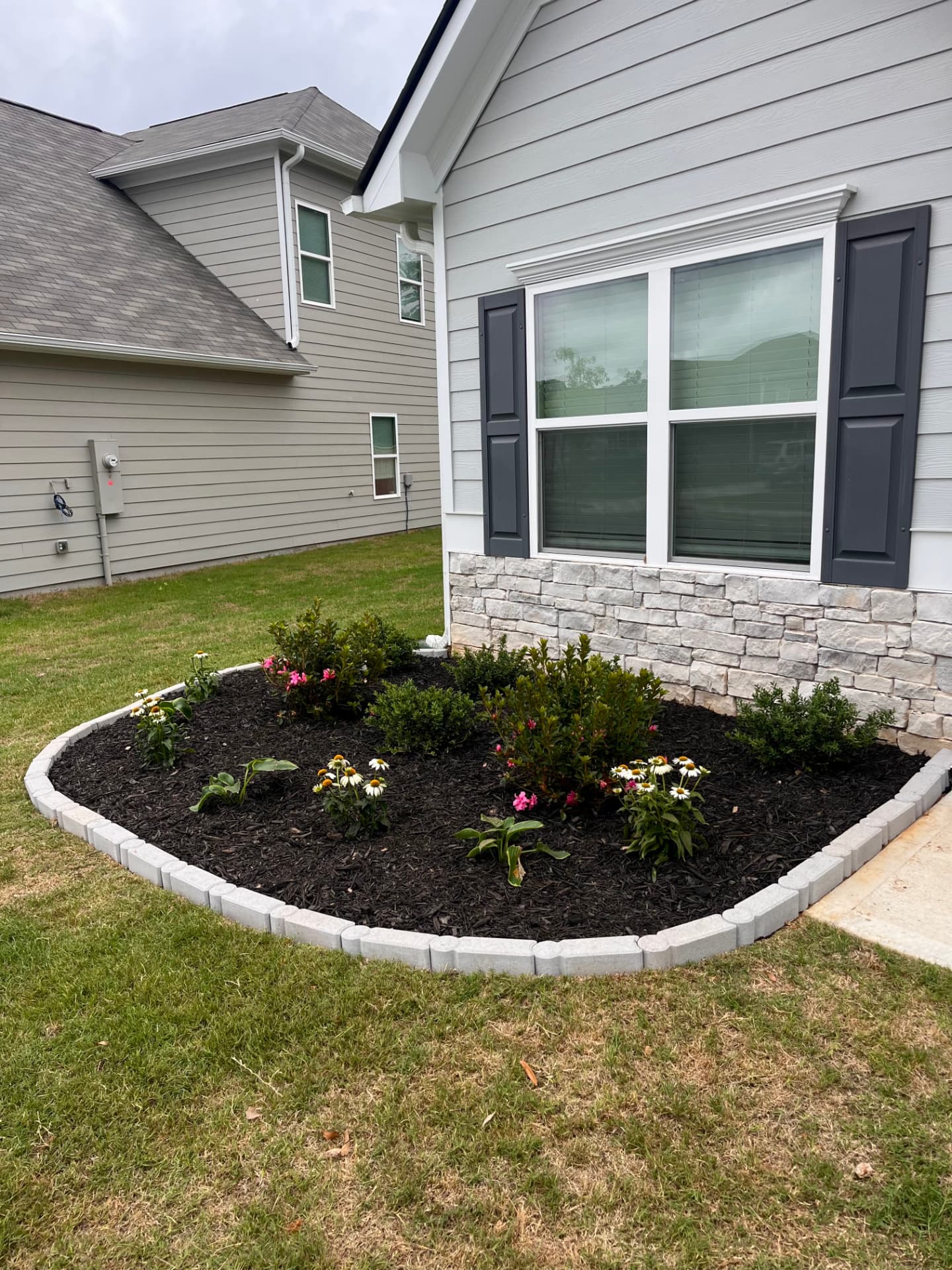 Fresh mulch bed with stone border around the house foundation